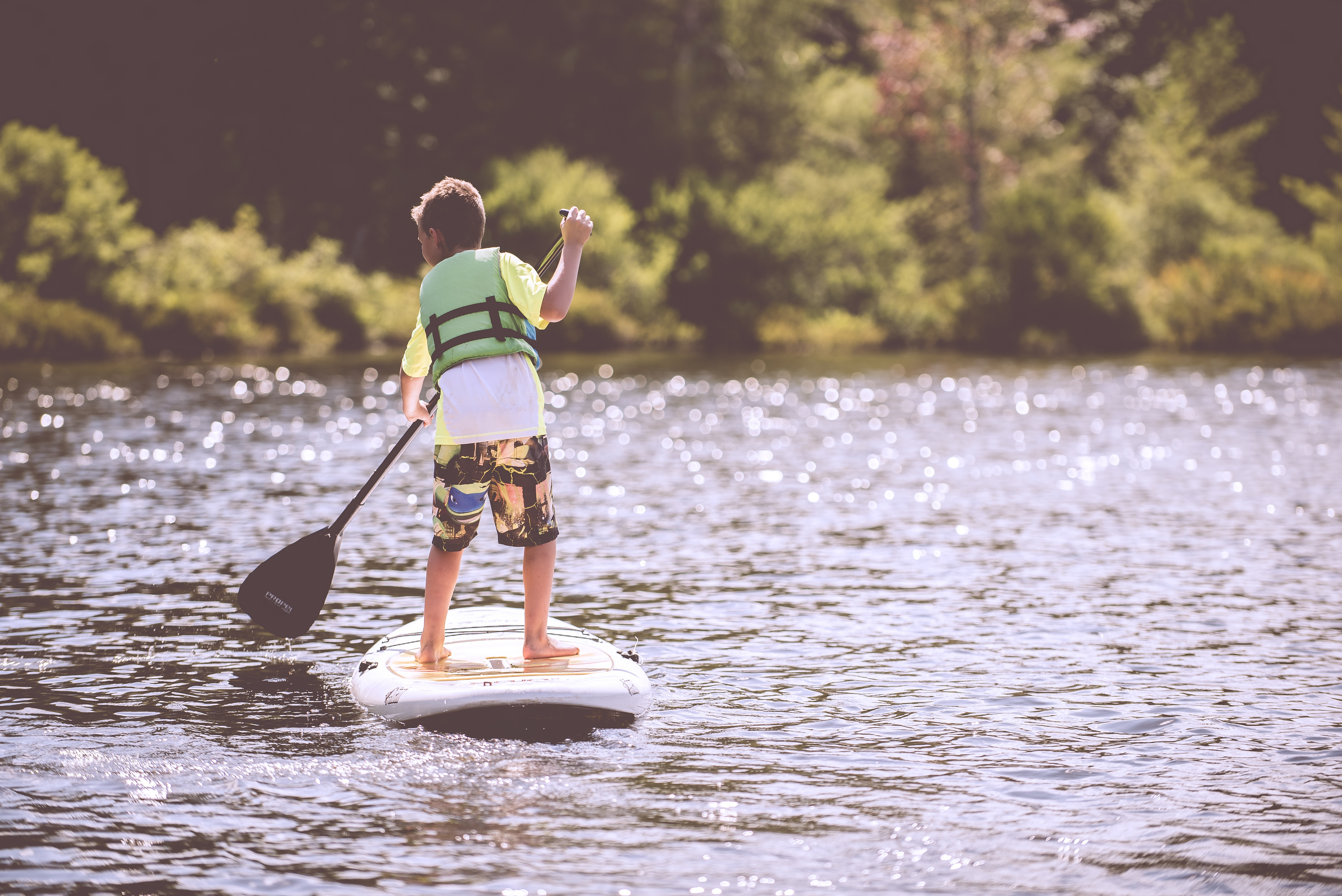 A young boy stand-up paddling in a river.