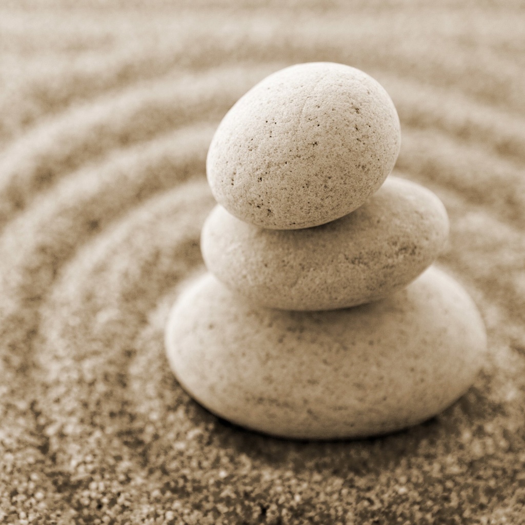 A picture of a set of rocks stacked atop curated sand.